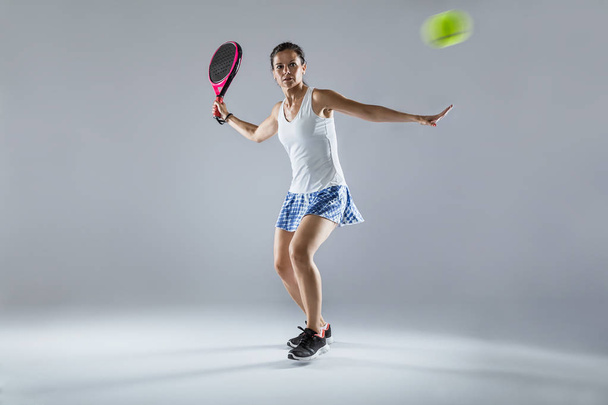 Shot of adult fitness woman playing padel indoor. Isolated on white. - 写真・画像