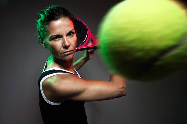 Portrait of adult fitness woman playing padel indoor. Isolated on black. - Foto, Imagem