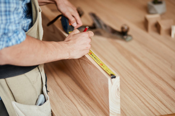 hand of a carpenter taking measurement of a wooden plank - Fotó, kép