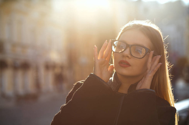 Outdoor portrait of wonderful blonde woman wearing glasses and coat, posing at the old sunny street. Space for text - Fotoğraf, Görsel