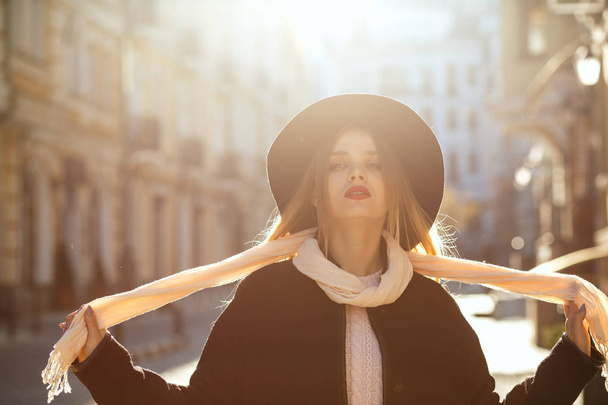 Retrato al aire libre de la gloriosa mujer rubia con sombrero, bufanda y abrigo, posando en la vieja calle con resplandor solar. Espacio para texto
 - Foto, imagen