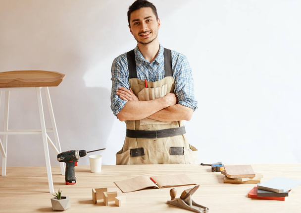 Confident young woodworker standing next to workbench in his carpentry workshop - Foto, immagini