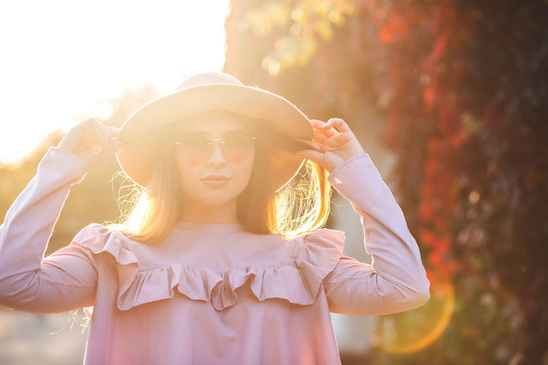 Bonita modelo bronceada con maquillaje natural con sombrero, gafas de sol y blusa rosa. Espacio para texto
 - Foto, imagen