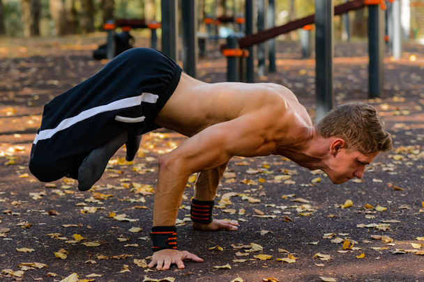 A handsome fitness man in a sportswear, guy doing gymnastics outdoor - Fotoğraf, Görsel