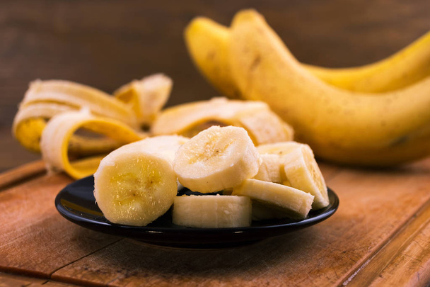Banane mûre tranchée en assiette sur fond de bois
. - Photo, image
