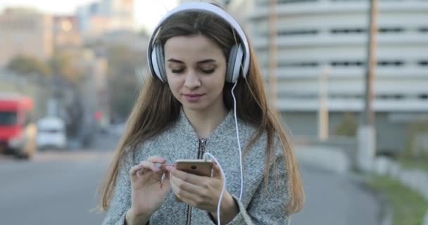 Woman listening to music with headphones in city - Filmati, video