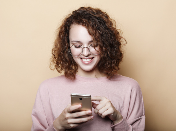 lifestyle, emotional and people concept: Young curly woman with smart phone - Fotó, kép