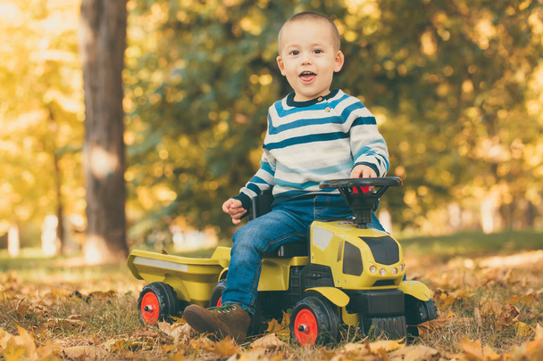 Kis boldog fiú tipegő szabadban park egy játék-teherautó vezetés - Fotó, kép
