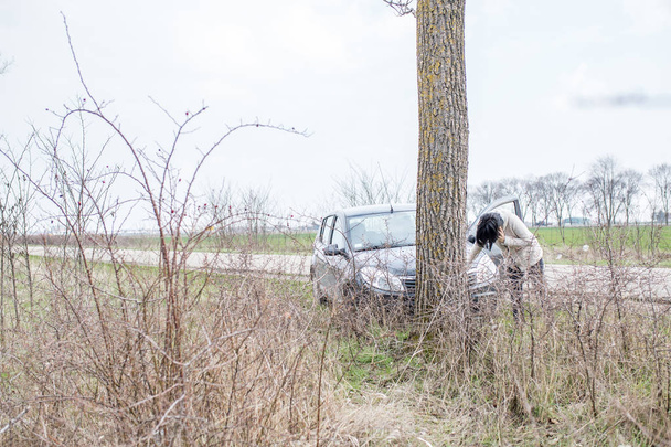 Zestresowany kobieta dzwoni do pomocy samochodu po wypadku na drodze. - Zdjęcie, obraz
