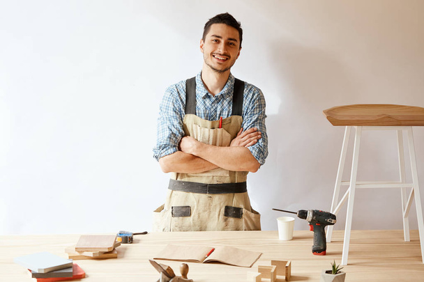 Confident young woodworker standing next to workbench in his carpentry workshop - Photo, Image