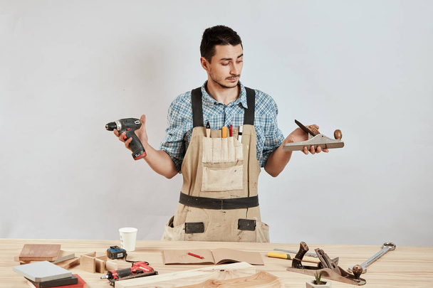 Emotional male carpenter in workwear and apron having confused puzzled look - Foto, Imagem
