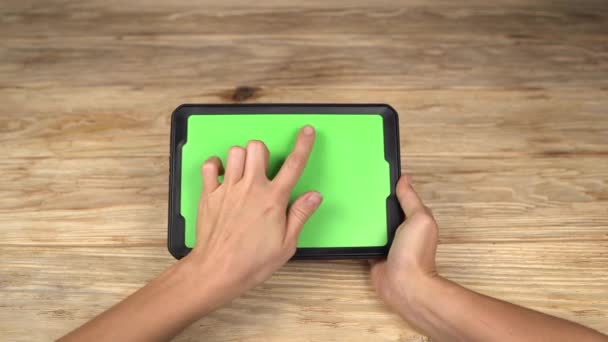 Una mujer sostiene una tableta PC con una pantalla verde para su propio contenido personalizado en el fondo de la mesa de madera
 - Metraje, vídeo
