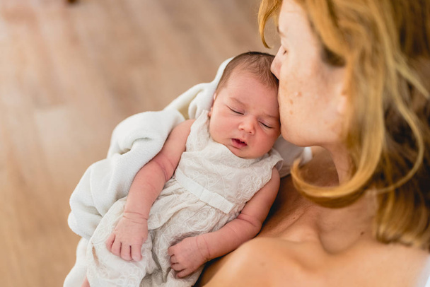 Neugeborenes im Arm blickt seine Mutter an. - Foto, Bild
