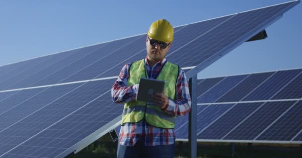 Adult engineer using tablet working among solar panels - Footage, Video