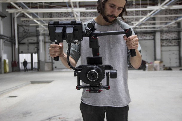 Professionele videograaf vasthouden van de camera op 3-axis gimbal. Videograaf gebruiken steadicam. Pro apparatuur helpt om hoge kwaliteit video zonder schudden. - Foto, afbeelding