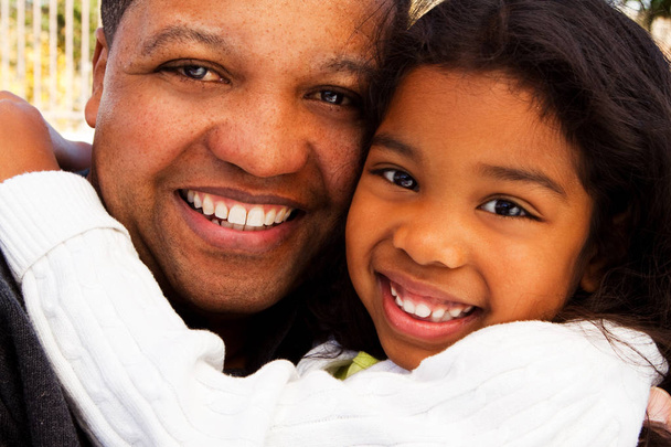 Biracial father and daughter laughing and smiling outside. - 写真・画像