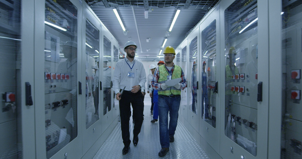 Trabajadores eléctricos caminando en la sala de control
 - Metraje, vídeo
