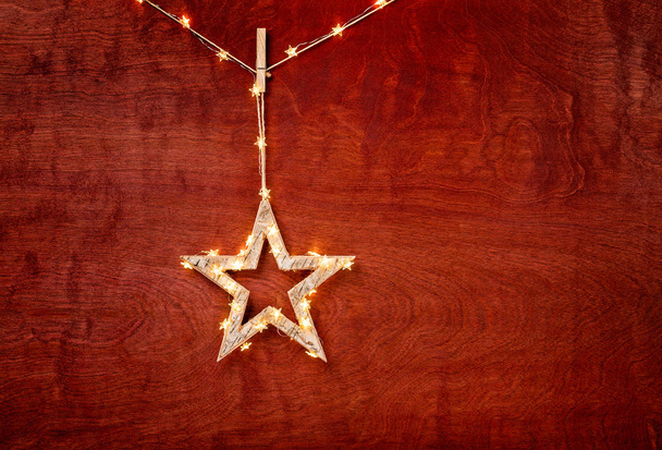 Décoration d'étoile de Noël rustique enveloppée de lumières sur un beau fond de bois rouge
 - Photo, image