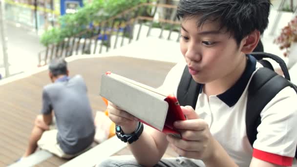 Asiático chico jugando en tableta ordenador con sonrisa cara, cámara lenta de tailandia chico viendo en tableta y relajante
. - Metraje, vídeo