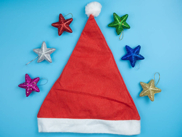Το Top view καπέλο Santa και Χριστουγεννιάτικο στολίδι και διακοσμήσεις σε μπλε φόντο. Ευτυχισμένο το νέο έτος διακοπές έννοια. - Φωτογραφία, εικόνα