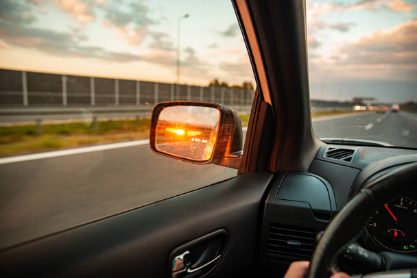 The Sun Setting In The Rear View Car Mirror High-Res Stock Photo