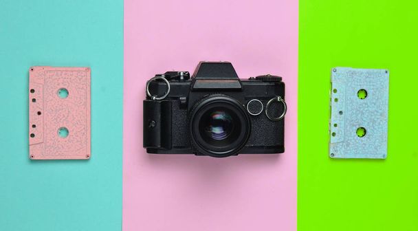 Ένα ρετρό Κασέτα ταινίας παστέλ χρώμα και μια φωτογραφική μηχανή ταινία με φόντο έγχρωμο χαρτί. Αντιγράψτε το χώρο. Μινιμαλιστική τάση - Φωτογραφία, εικόνα