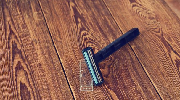 Maquinilla de afeitar de plástico en una mesa de madera. Vista superior
 - Foto, imagen