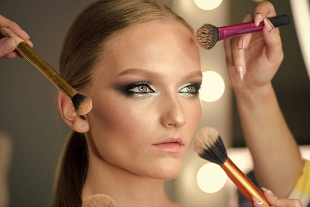Many hands doing makeup to young woman. - Foto, Bild