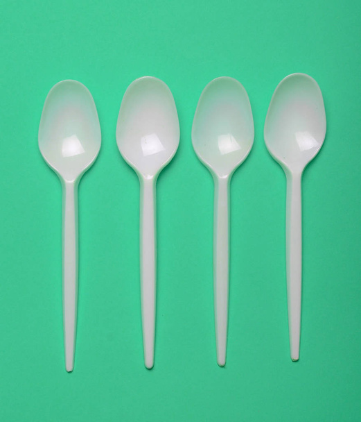 Plastic spoons for a picnic on a green background. Top view - 写真・画像