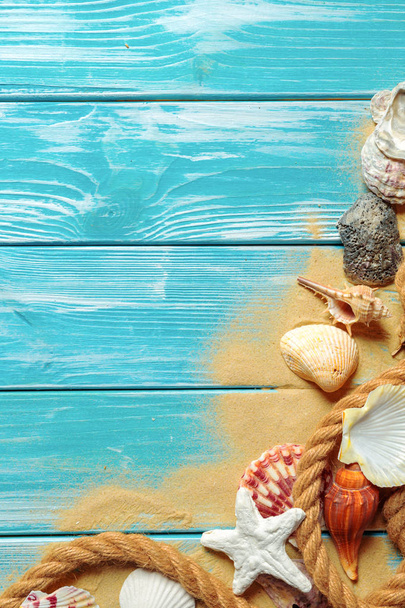 sea rope with sea shells on sea sand on blue wooden background. Top view - Foto, imagen