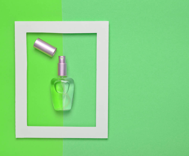 A perfume bottle in a white frame on a colored pastel background. Minimalist trend. Top view - Photo, Image