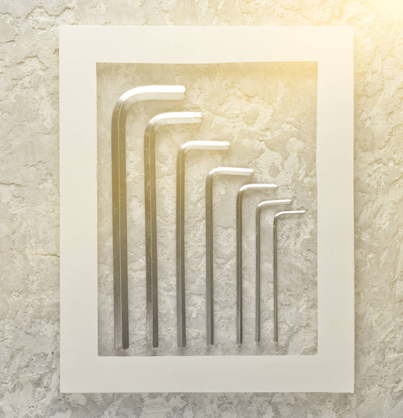 Hexagonal wrench in a white frame on a gray concrete background. Minimalist trend. Copy space - Zdjęcie, obraz