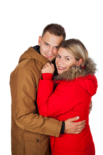 Молодая пара в красно-коричневой зимней куртке парки позирует на изолированном фоне - Сезонная модная одежда
 - Фото, изображение