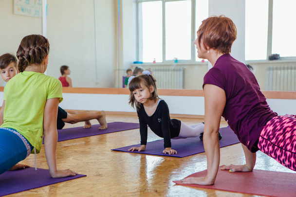 Yoga lesson for kids with teacher in a room - Zdjęcie, obraz