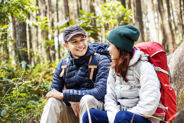 Smiling asian couple hikers with backpack looking at each other on forest - Foto, Imagen