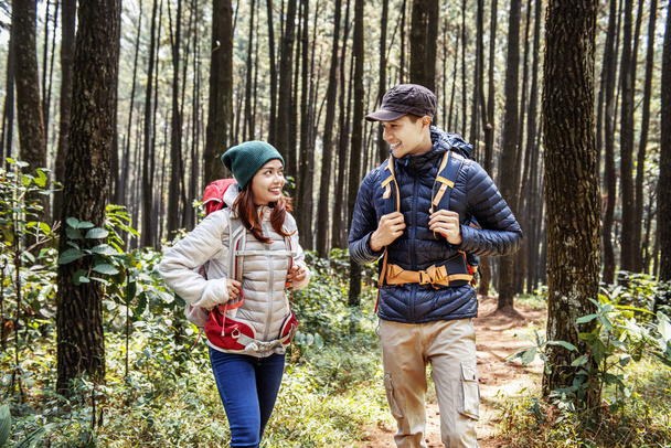 Young asian couple hikers with backpack walking on forest path - Фото, зображення