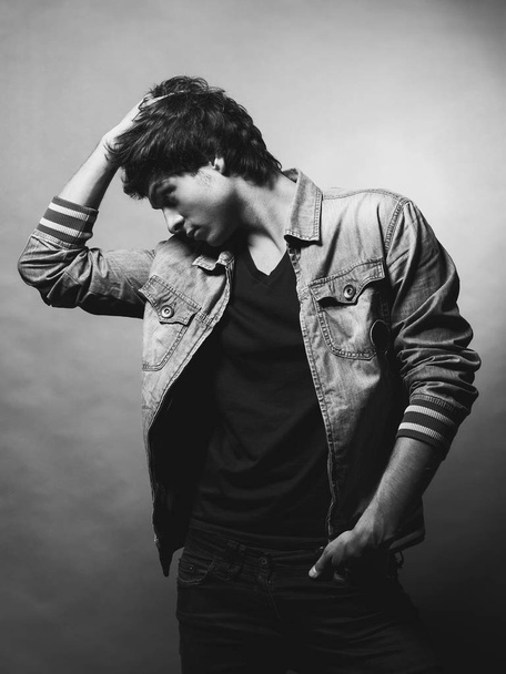Portrait of Handsome Young Man. A Men in a Denim Jacket Posing on a Gray Background. Black and White Photo - Foto, Imagen