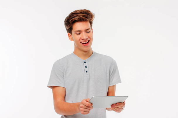 attraktiver junger Mann hält Tablet in der Hand und lächelt auf weißem Hintergrund - Foto, Bild