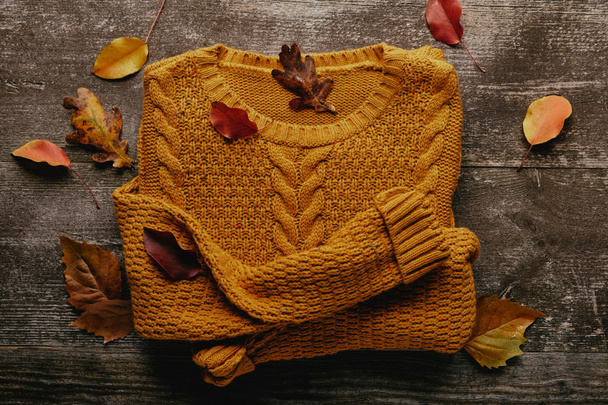 flat lay with fallen leaves and orange sweater on wooden tabletop - Photo, Image