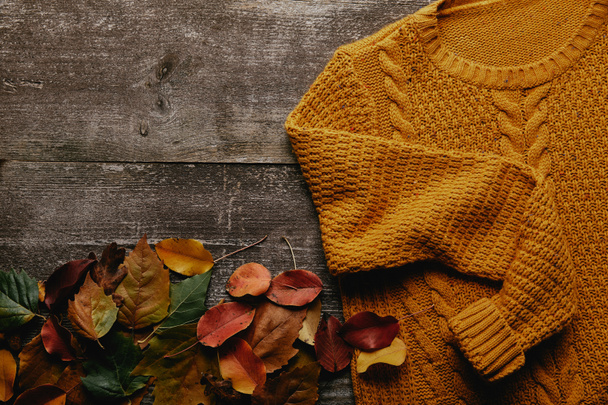 flat lay with fallen leaves and orange sweater on wooden tabletop - Fotoğraf, Görsel
