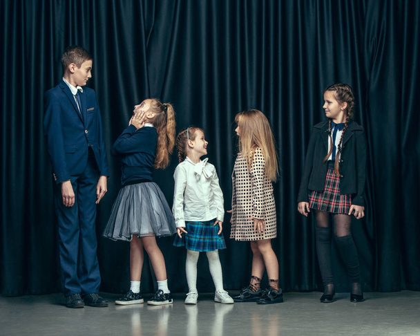 Cute stylish children on dark studio background. The beautiful teen girls and boy standing together - Valokuva, kuva