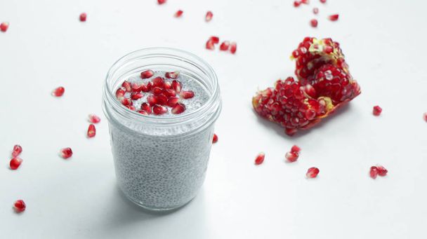 Pudín de semillas de chía con semillas de granada en un frasco de vidrio sobre un fondo blanco. Concepto de comida saludable. Comida vegana
 - Foto, Imagen