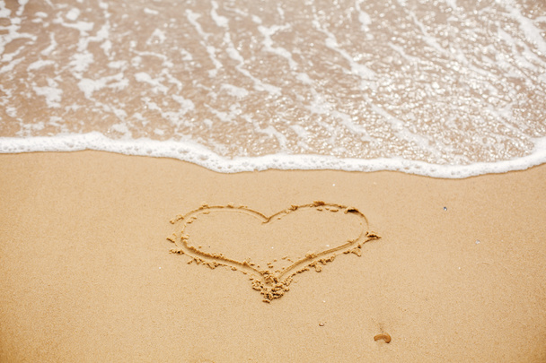 Corazón escrito en playa de arena con olas cerca del mar. Concepto de amor. Feliz día de San Valentín. Luna de miel para recién casados. San Valentín. Espacio para el texto. Felices fiestas
 - Foto, Imagen