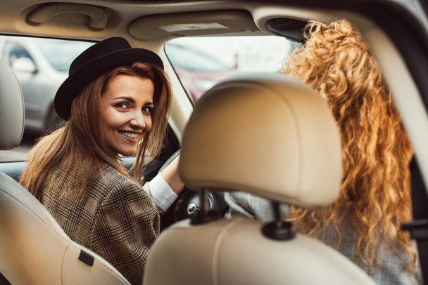彼女の女友達が近くに座っている間車を運転して笑顔の女性の肖像画 - 写真・画像