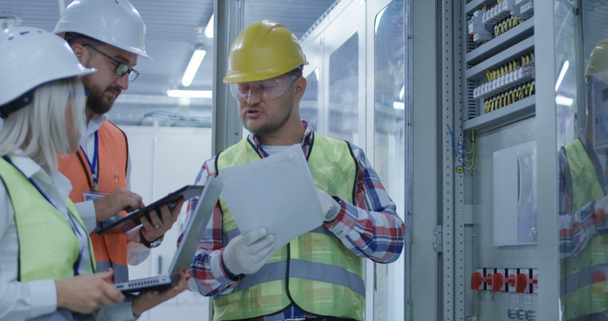 Kolme sähköalan työntekijää tarkastamassa asiakirjoja
 - Materiaali, video