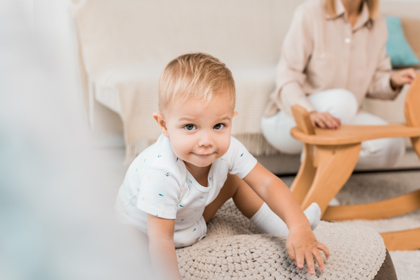 adorable toddler sitting and looking at camera with mother on background - Foto, Bild