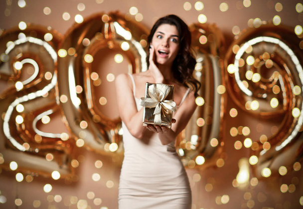 A boldog meglepett nő, kezében a jelen box: új év party portréja - Fotó, kép
