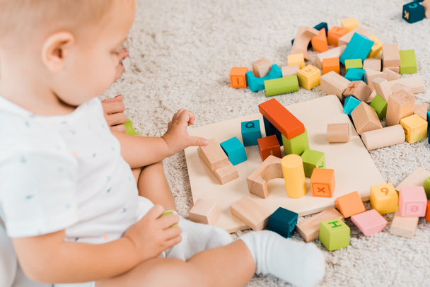 side view on adorable toddler playing with colorful cubes - Photo, Image