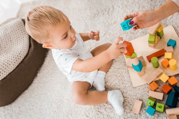 angle view on adorable toddler playing with colorful cubes in nursery room - Φωτογραφία, εικόνα