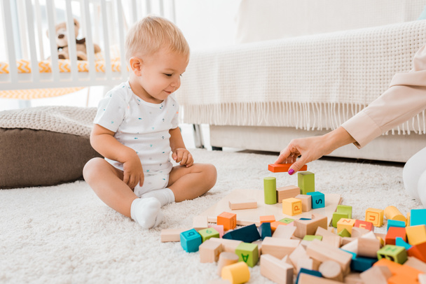 entzückendes Kleinkind spielt mit bunten Würfeln im Kinderzimmer - Foto, Bild